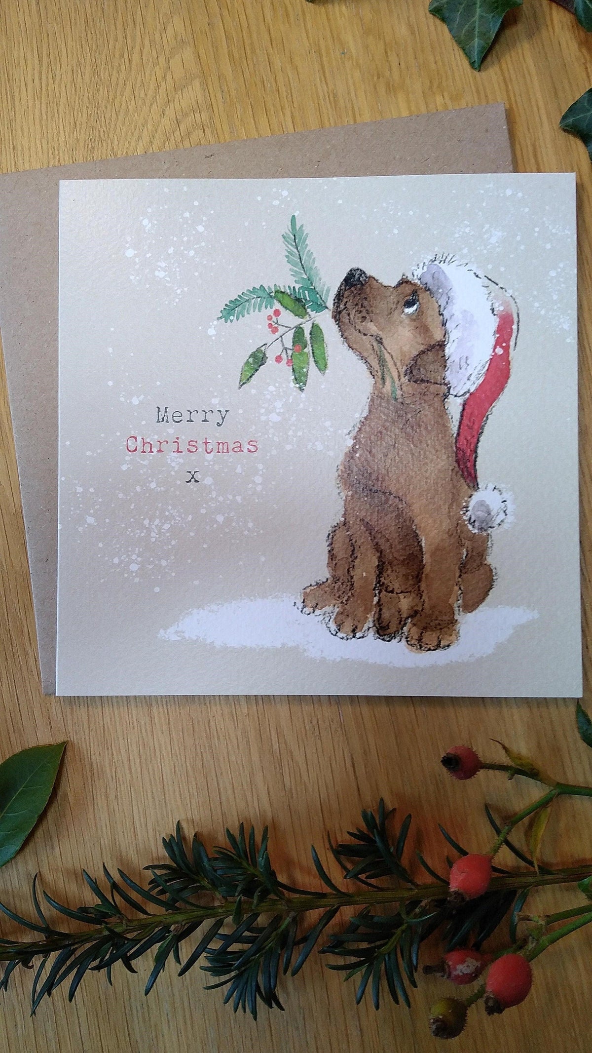 Christmas Card - Merry Christmas - Brown Labrador Puppy Looking Up with Christmas Foliage in It's Mouth.